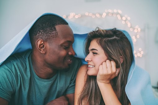 Portrait of cute couple lying down in bed