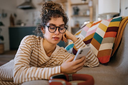 young woman texting on the couch