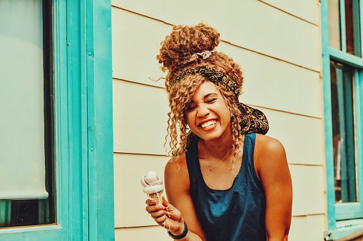 Woman eating ice cream outdoors in summertime.