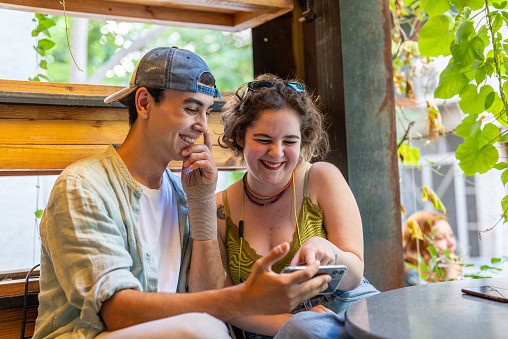 Young friends watching mobile device screen in a cafe