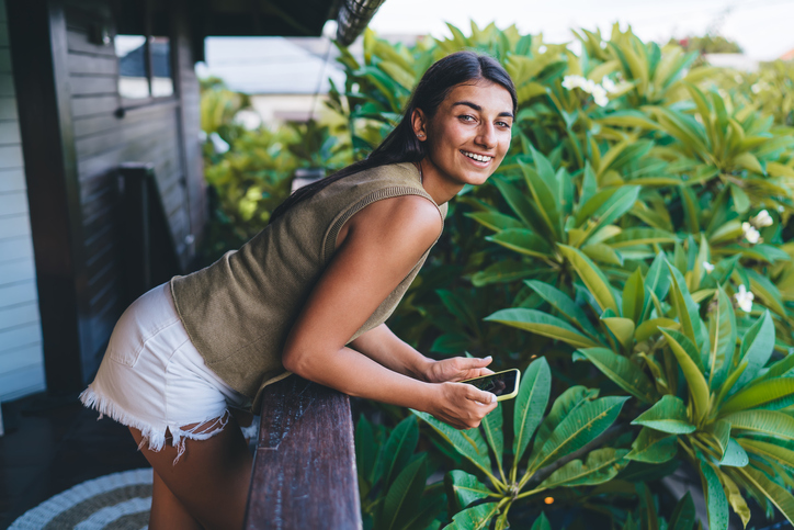 Smiling woman leaning over balcony at tropical hotel.