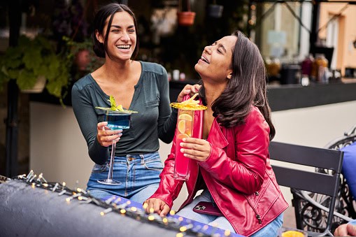 Happy girlfriends drinking cocktails at brewery bar