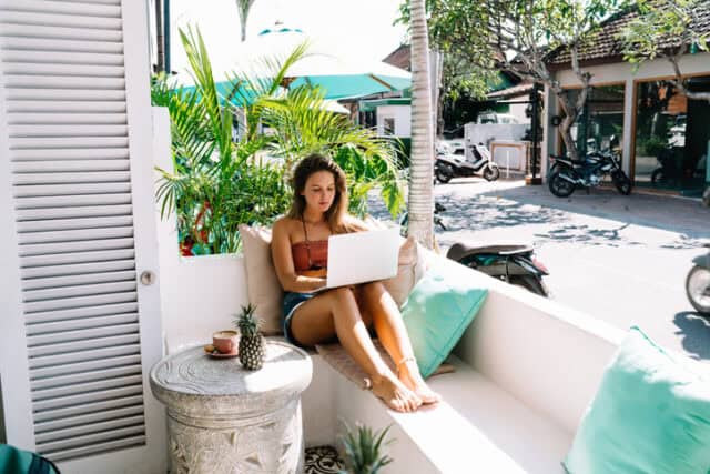 woman working on laptop on beach vacation