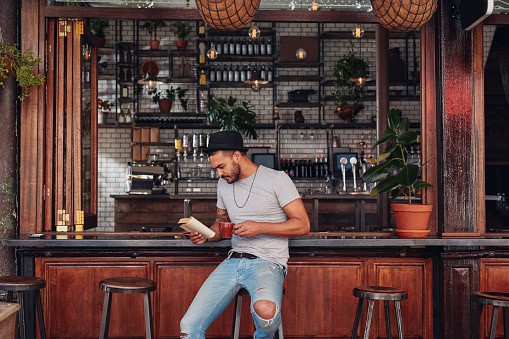 man reading book at bar
