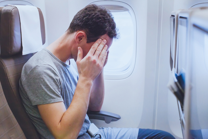 Man on a airplane head in hands.