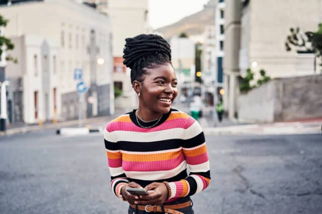 laughing girl texting on city street