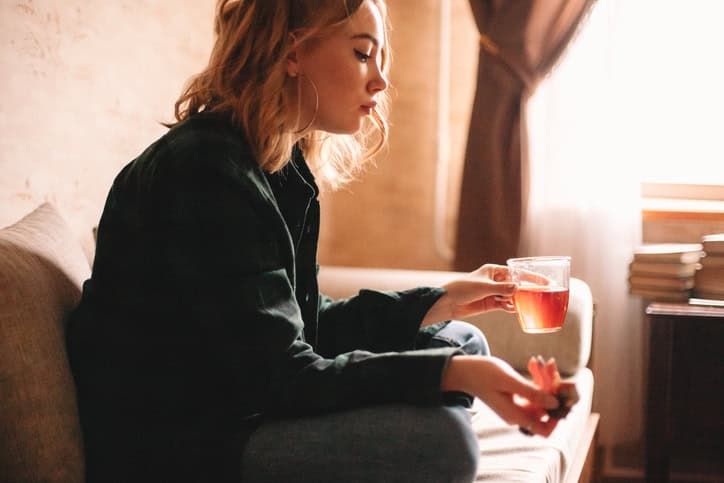 sad woman with tea on couch