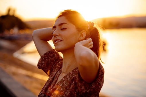 Young woman by the sea at sunset,