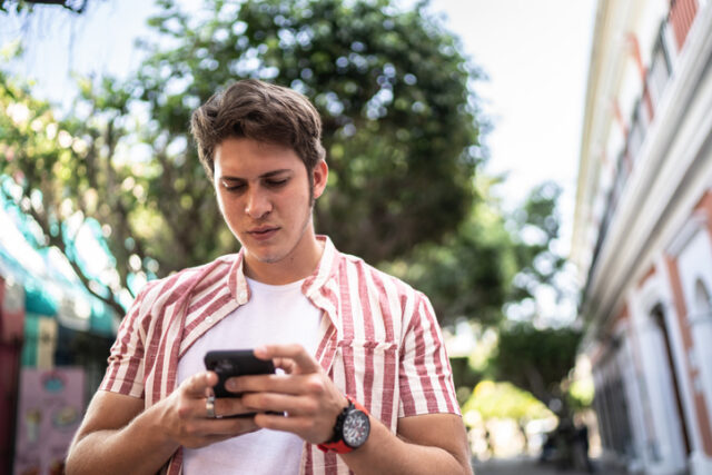 skeptical guy texting while walking outside