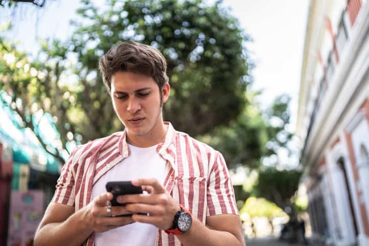 skeptical guy texting while walking outside