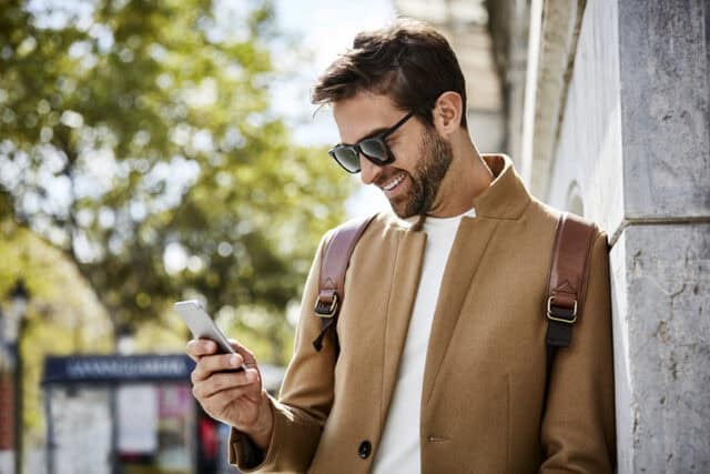 smiling trendy guy texting in sunglasses
