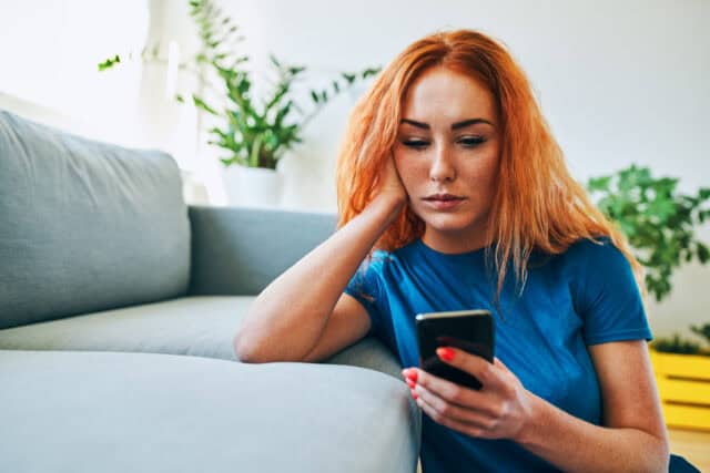 serious woman texting on couch
