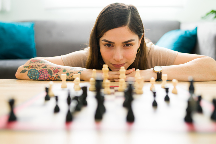 Woman studying chess board.