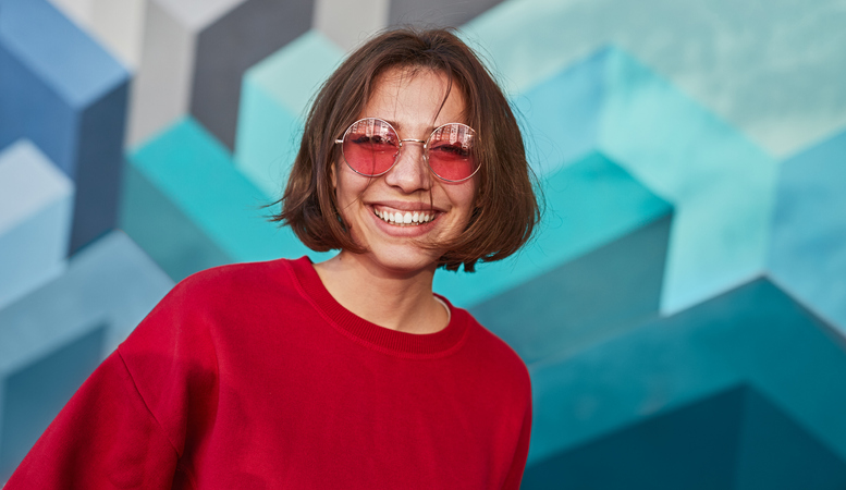 Smiling woman wearing tinted sunglasses.