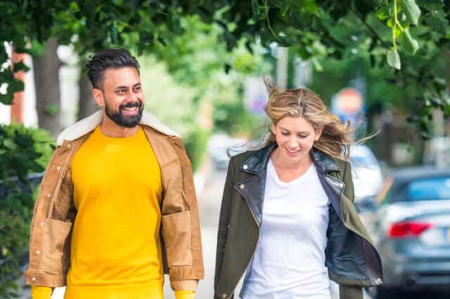 millennial couple walking down city street