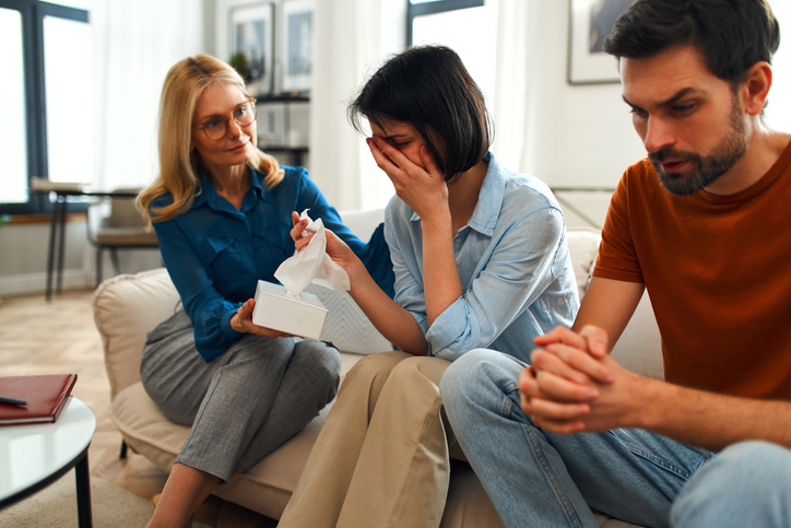Family comforting an upset woman.