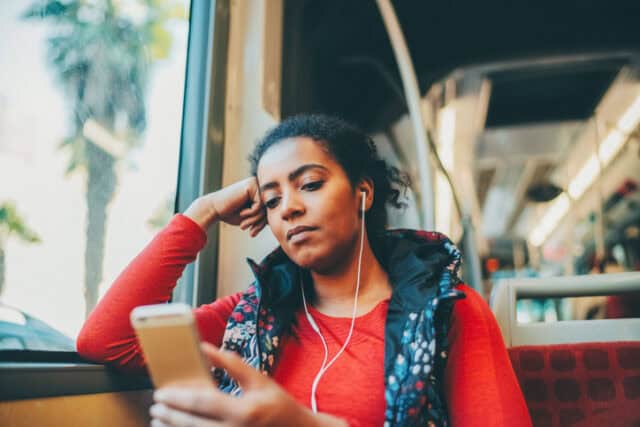 woman staring at phone while riding bus