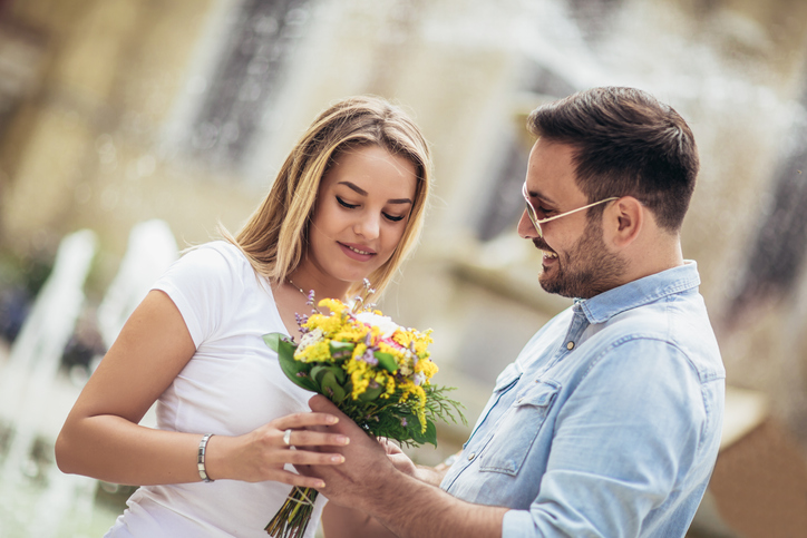 Man surprising woman with flowers.