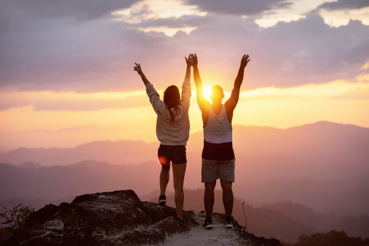 Happy couple at sunset on mountain top.