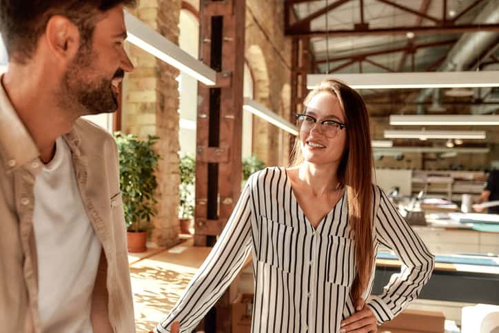 Office life. Two modern young people talking about something while standing in the creative office