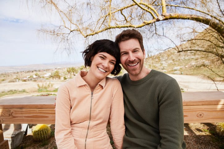 Smiling young couple sitting outside on their porch