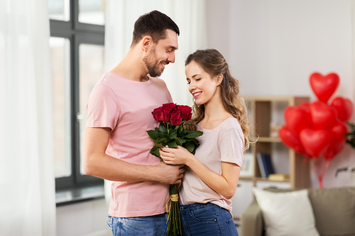 Man giving a woman red roses in a romantic gesture.