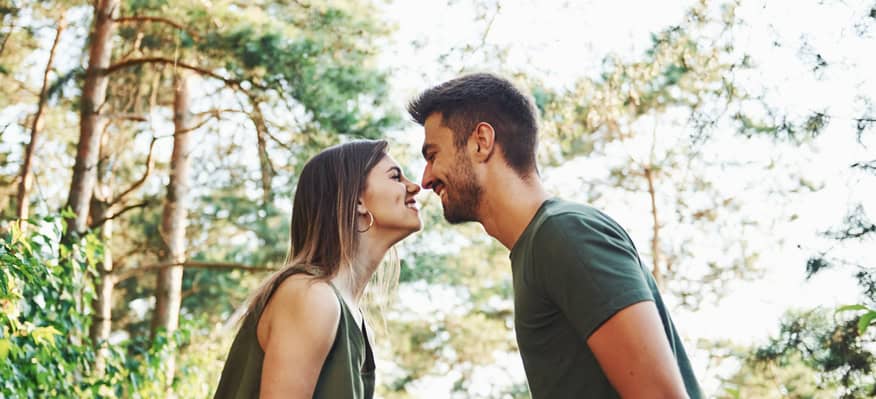 Side view. Beautiful young couple have a good time in the forest at daytime
