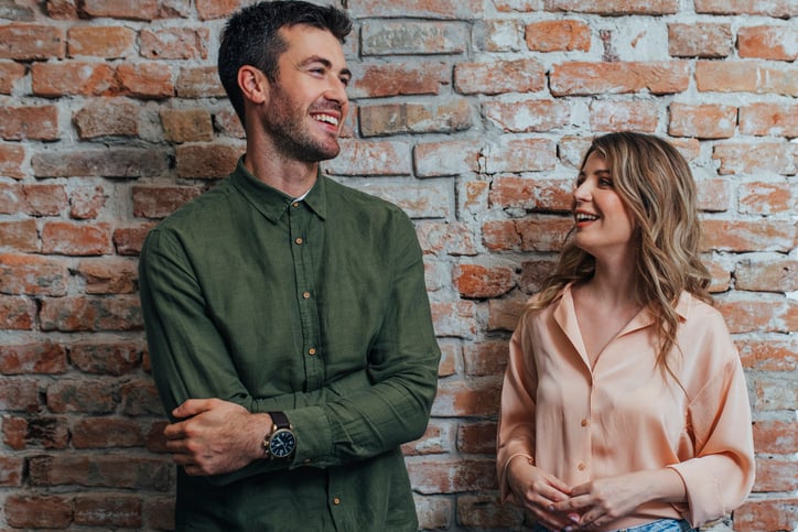 Young Man and Woman Smiling and Chatting at the Office