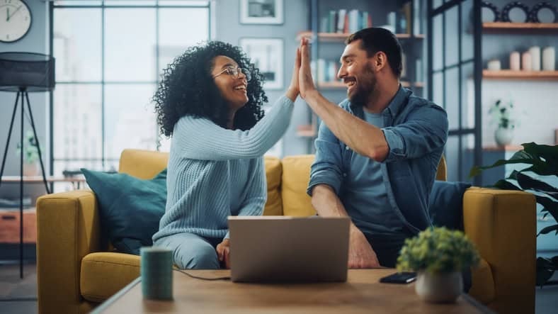 Colleagues sitting together on a couch giving a high five.
