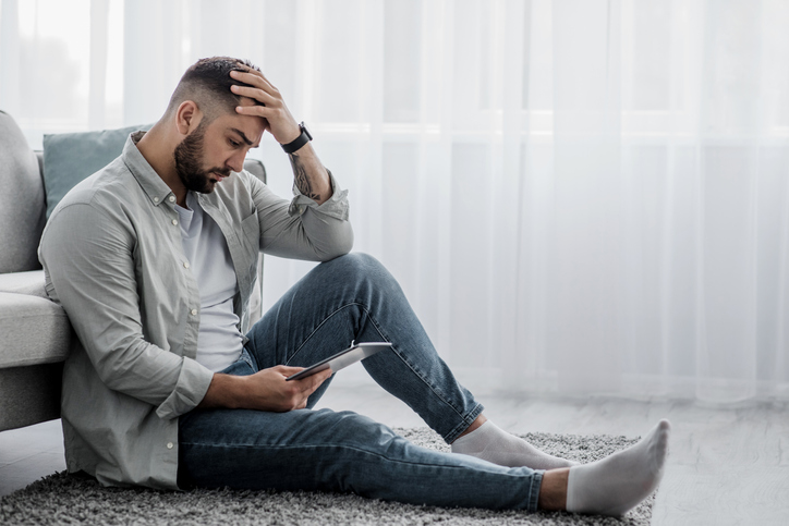 sad man sitting on living room floor