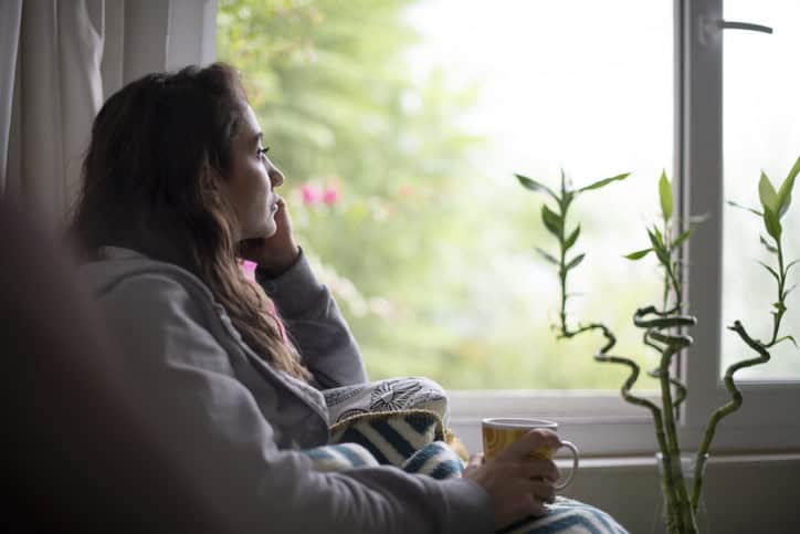 depressed woman sitting by window