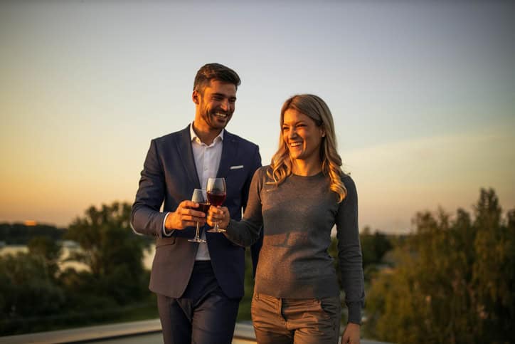 Happy business colleagues walking while drinking wine outdoors.