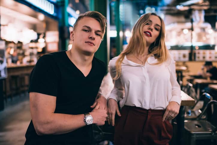 Young man and woman standing near table in cafe