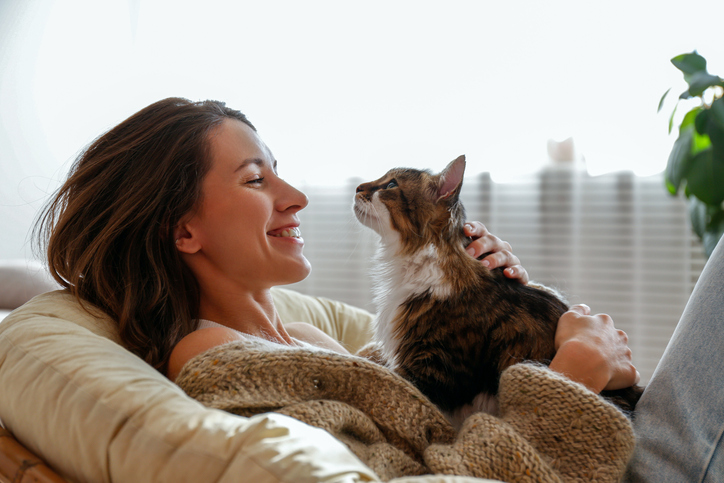 Woman holding a cute cat with green eyes.