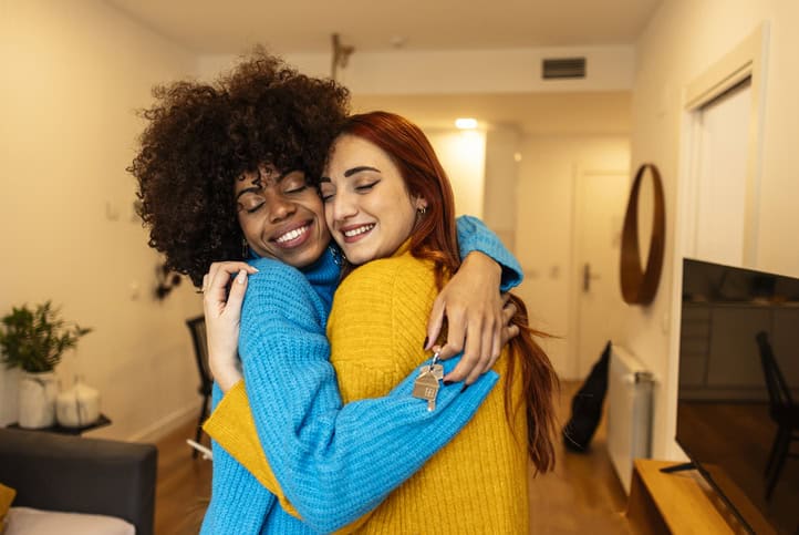 Multiracial lesbian girlfriends embracing with eyes closed. Women couple in their new home