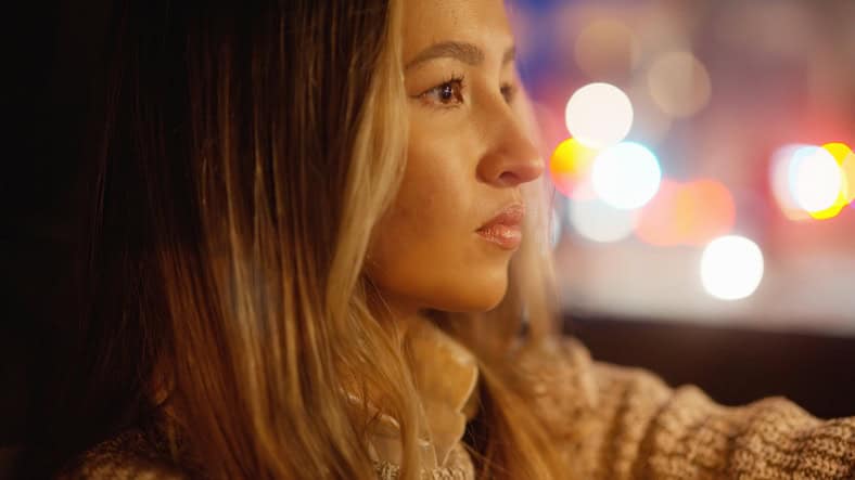 Woman with a serious look in her eyes, driving a car at night