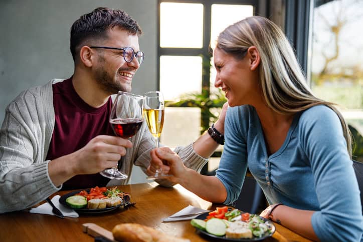 Cheerful couple toasting with alcohol during a meal in dining room.