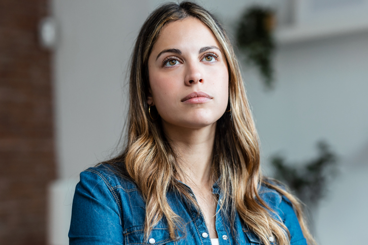 Portrait of beautiful young woman thinking at home.