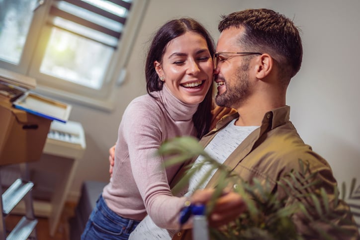 Smiling couple unpacking boxes in new home.