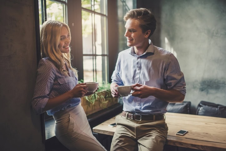 Handsome young man and attractive young woman are spending time together. Romantic couple in cafe is drinking coffee and enjoying being together.