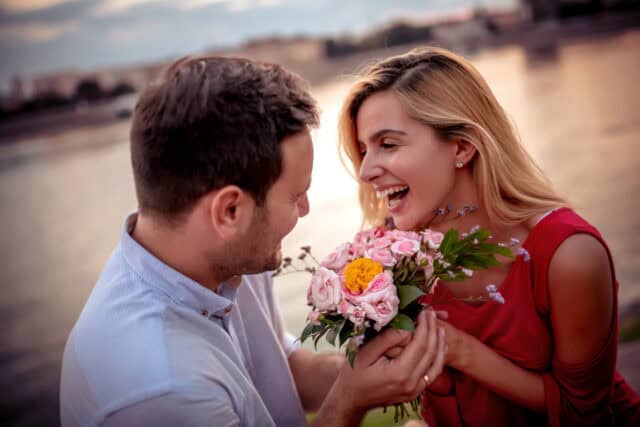 Young man is giving beautiful bouquet of flowers to his girlfriend.