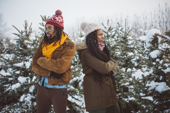 Couple arguing near Christmas trees.