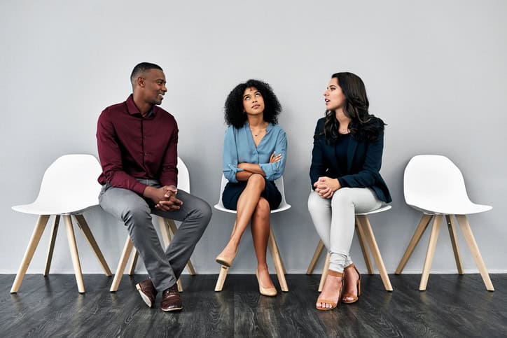 Studio shot of a young businesswoman looking annoyed listening to a conversation in a waiting room against a grey background