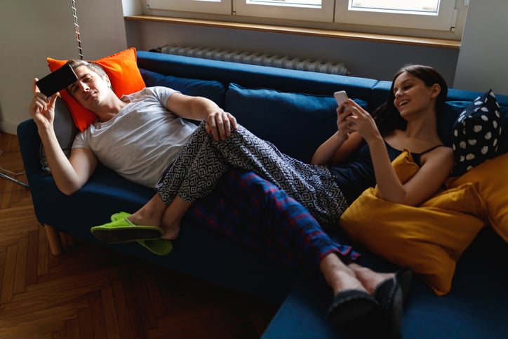 Couple being lazy on the couch in pajamas.