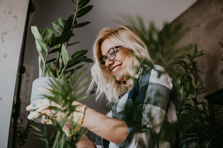 Woman watering one of her plant arrangements.