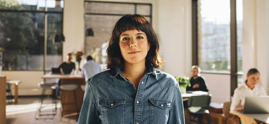 Portrait of freelancer standing in co-working space. Confident businesswoman looking at camera.