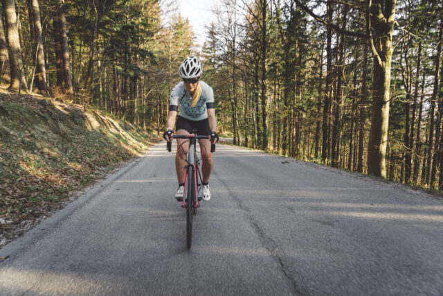 One woman cyclist cycling on a country road. Woman cycling alone on a beautiful sunny day.