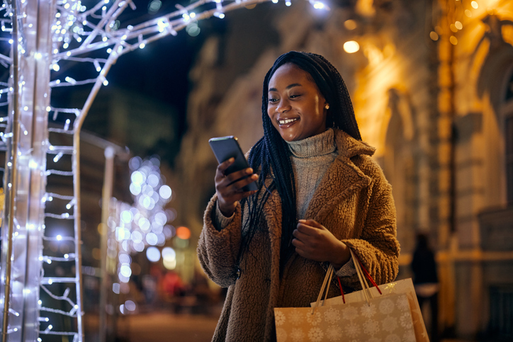 Young woman standing on the city streets with shopping bags at Christmastime.