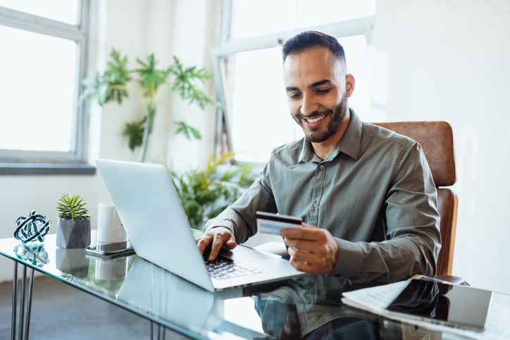 Businessman in office, using credit card to pay online.