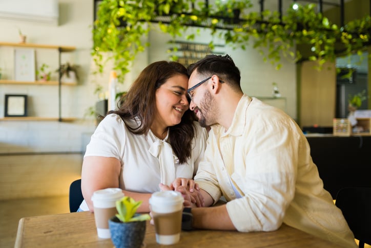 Smiling couple in love holding hands during a date at a cafe and having a romantic moment